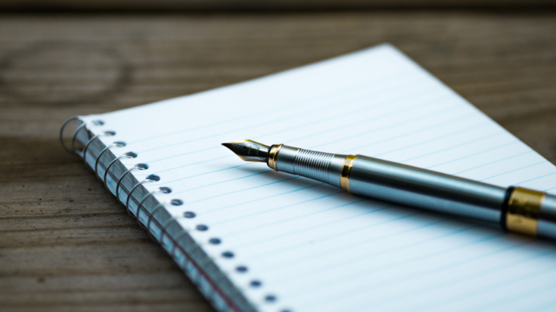 A blank page with a pen laying across it.